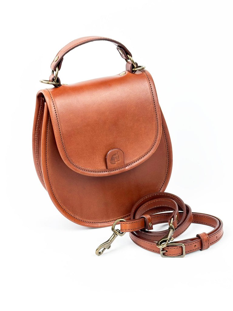 Brown leather handbag with a strap on a white background. 